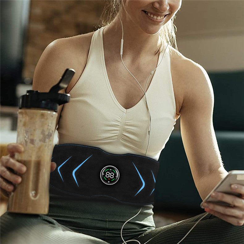 Woman wearing a black waist trainer, holding a blender, and using a phone.