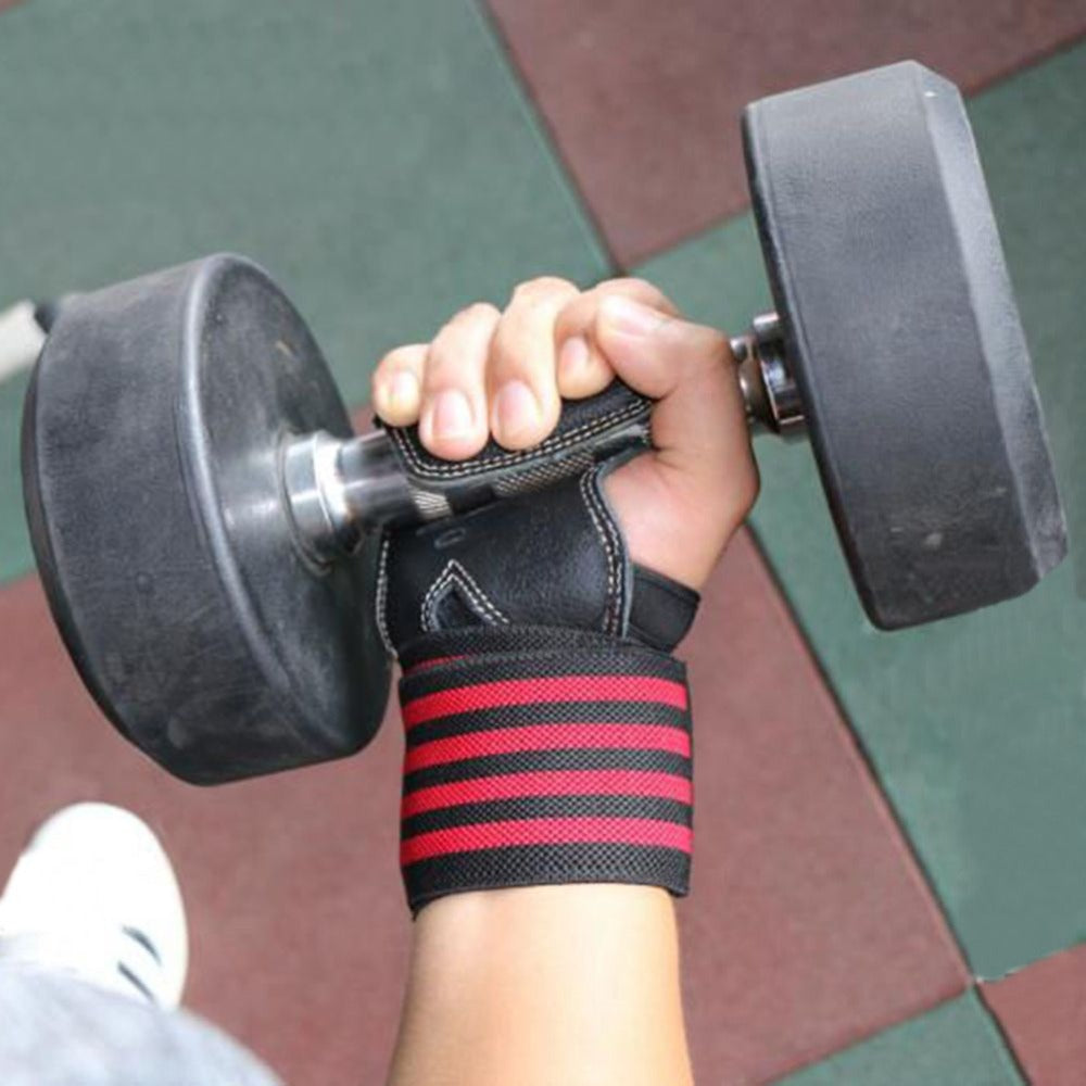 Hand holding a dumbbell with a red and black wrist support on a blurred gym floor background