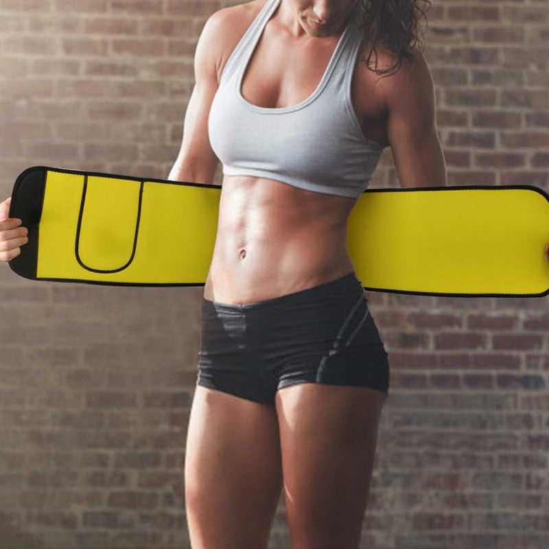 Person holding a yellow and black weightlifting belt against a brick wall.
